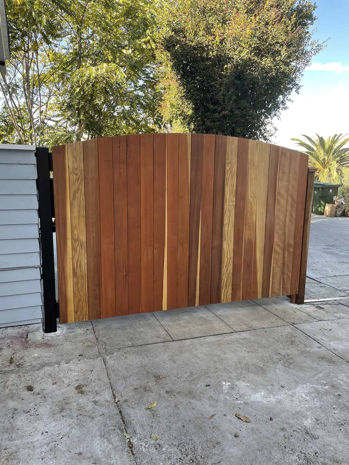 Arched redwood plank driveway gate