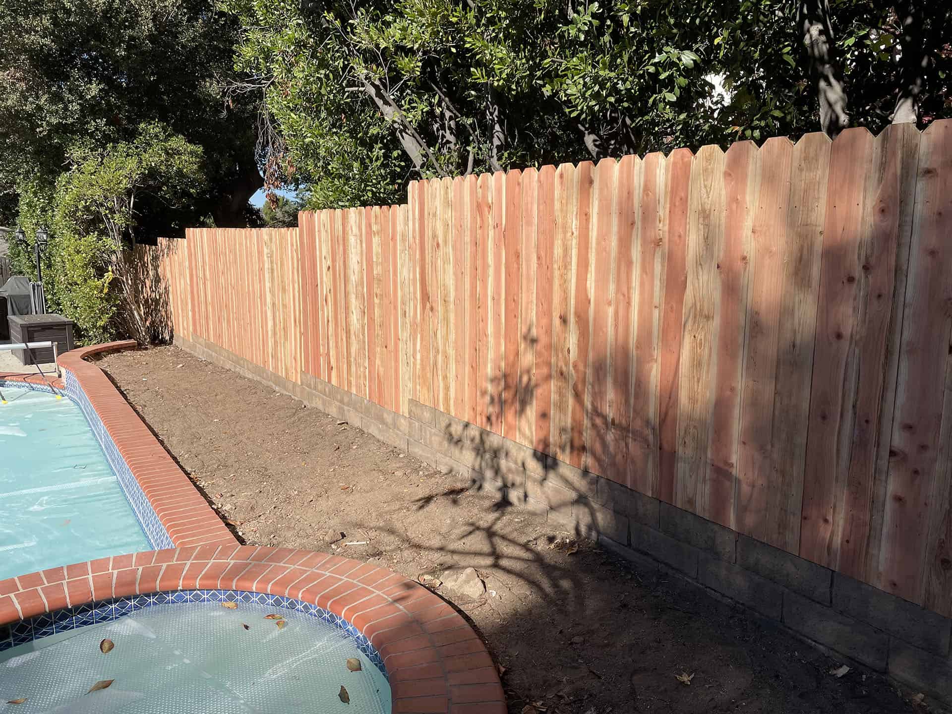 Redwood dog-ear fence in a poolside backyard