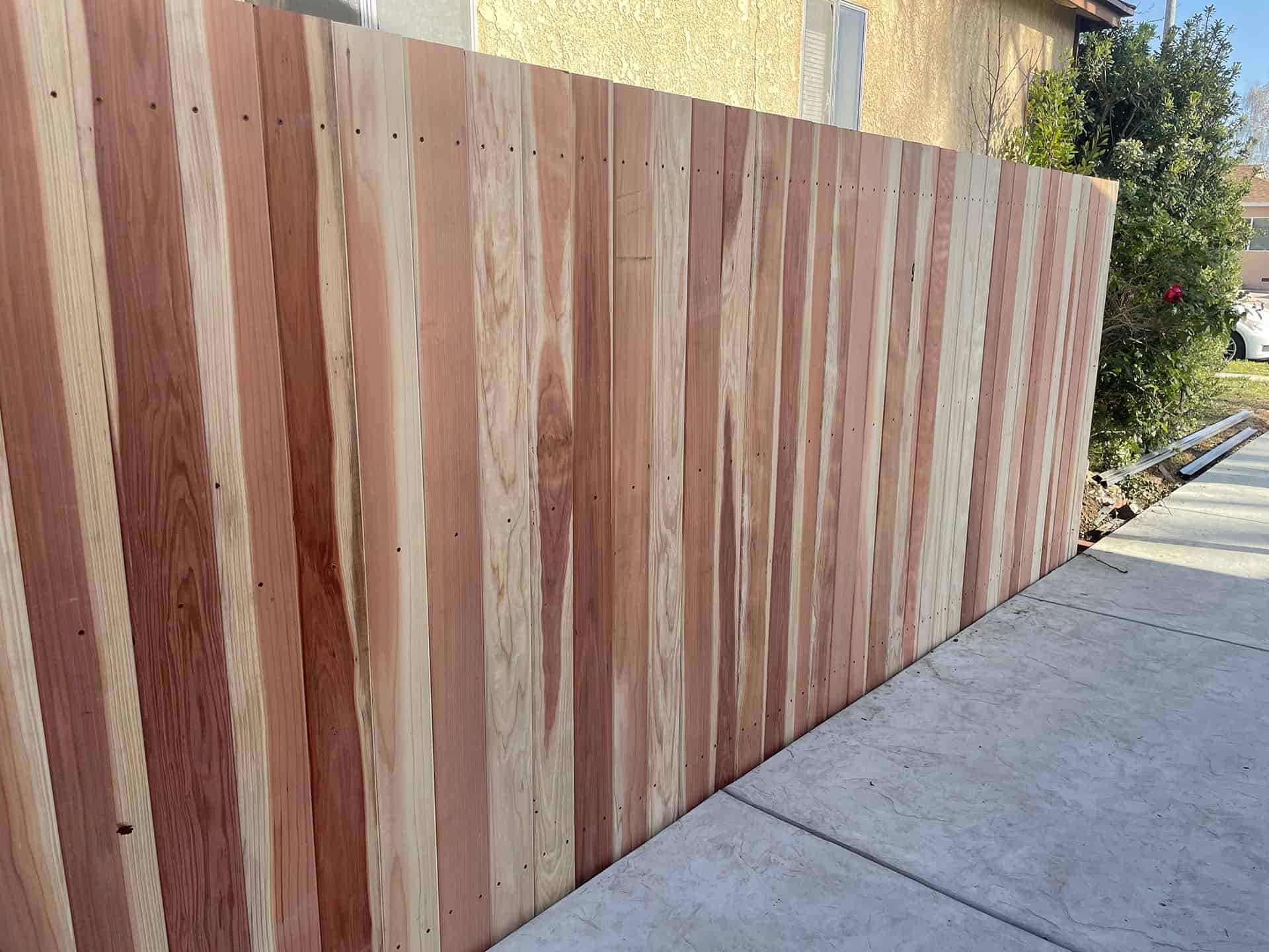 Vertical redwood privacy fence beside a driveway