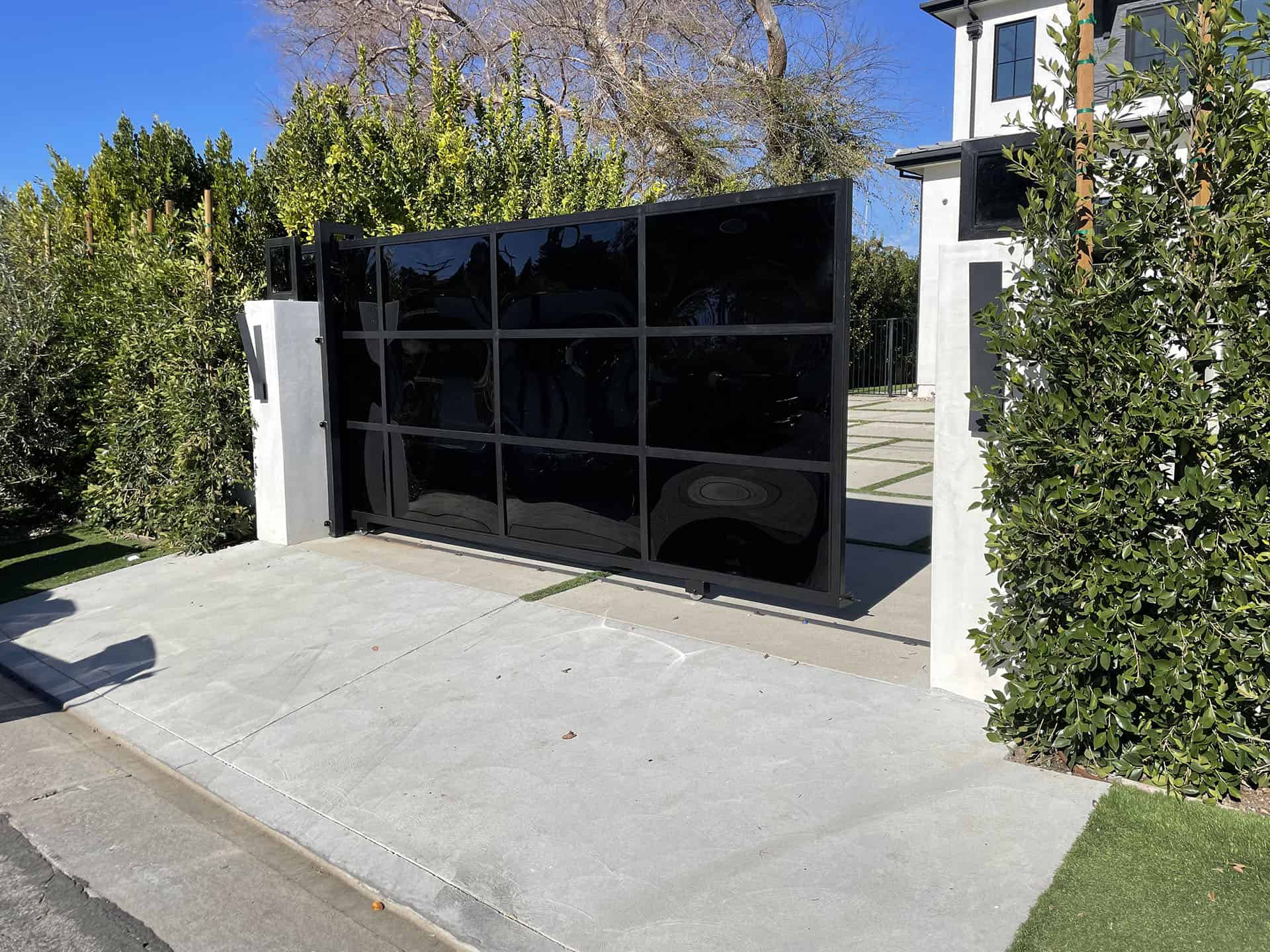 Blackened steel and smoked glass sliding driveway gate at an Encino residence