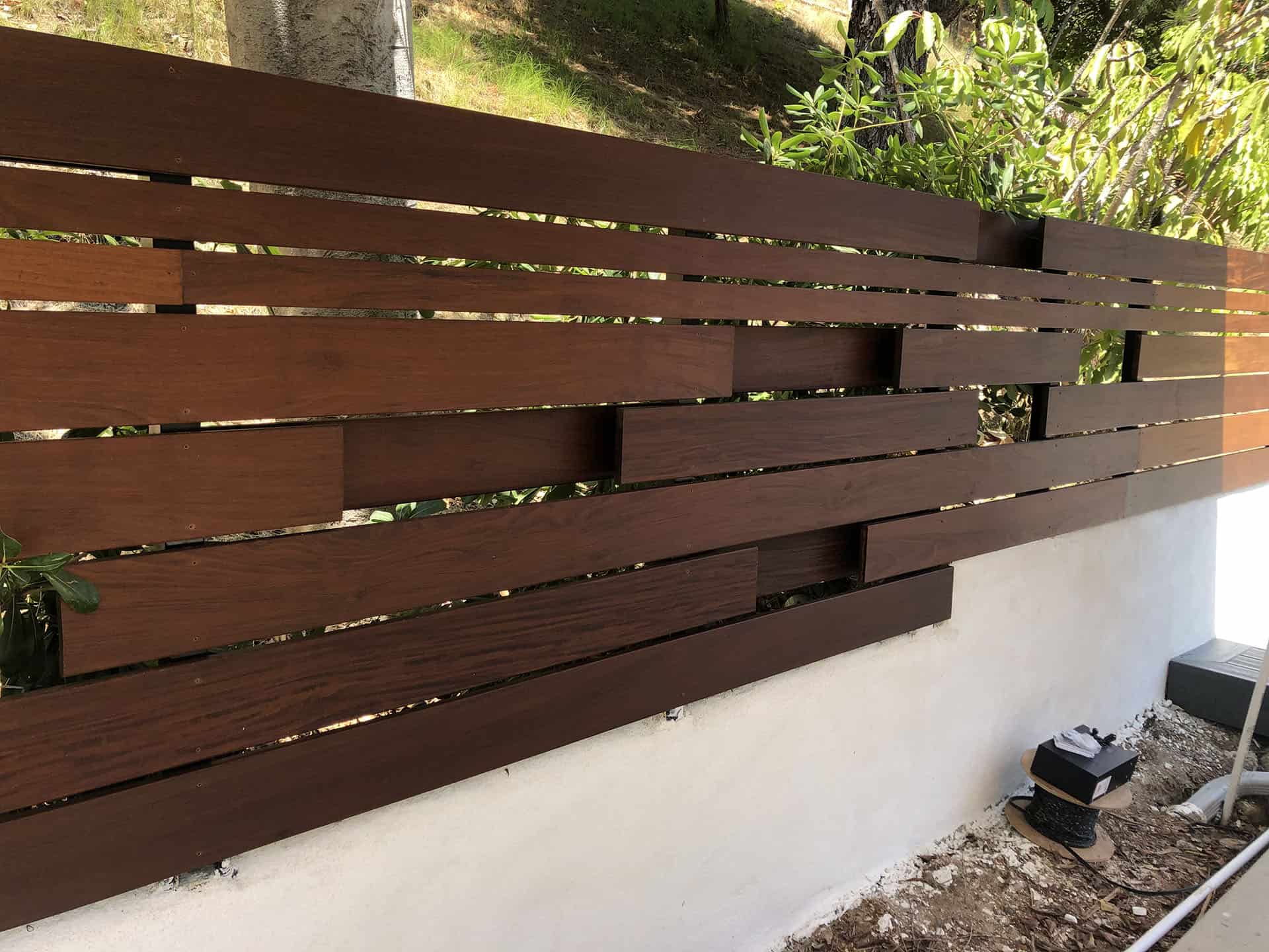 Dark walnut horizontal slat fence stepping down a hillside grade